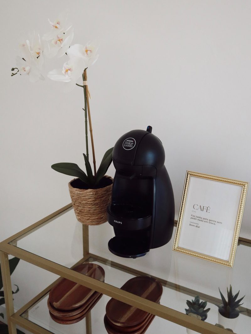 Cantinho do café, com máquina, orquídea e moldura dourada