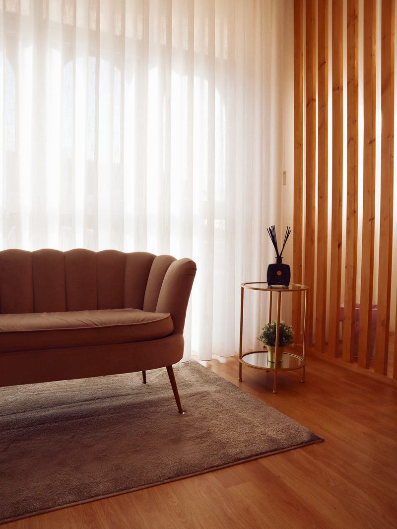 Sofá de espera junto à janela, com mesa de apoio dourada