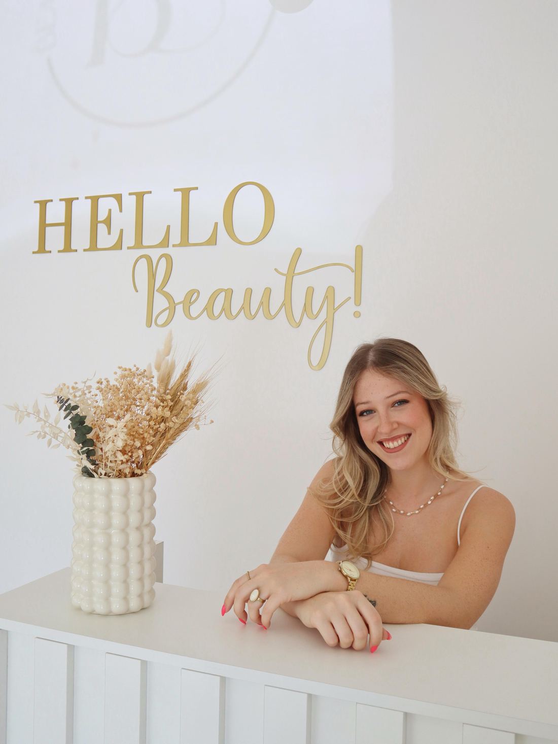 A Sofia à receção do Beauty Concept, com o letreiro dourado Hello Beauty na parede